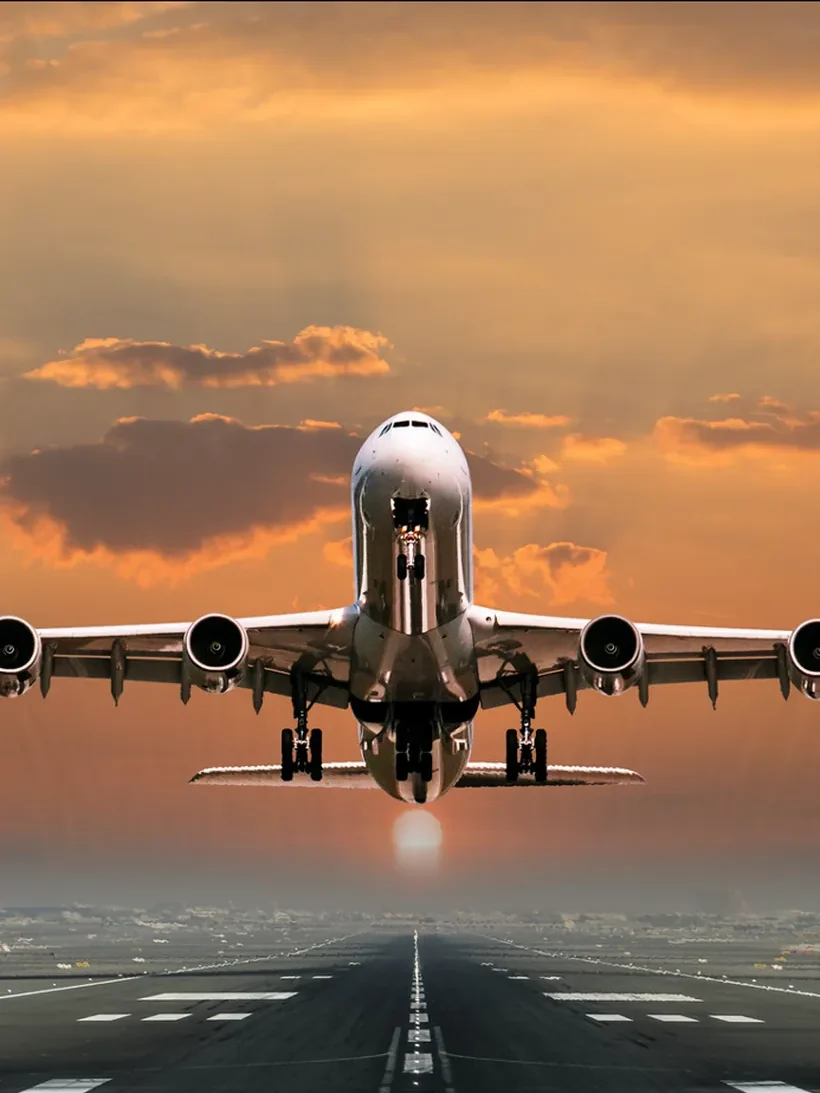 An airliner lifting off a runway at sunset